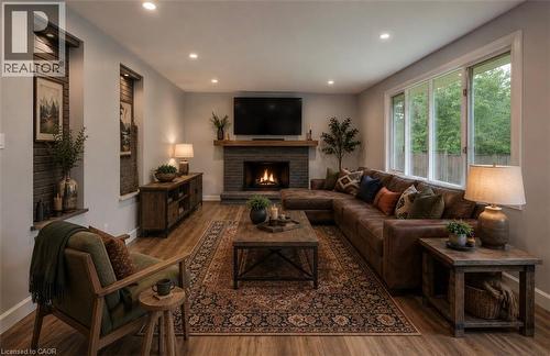 Recessed fireplace with a wood mantel, wood-finish flooring, recessed lighting, expansive windows, and built-in wall niches with brick-finish backing - 244 Royal Street, Waterloo, ON - Indoor Photo Showing Living Room With Fireplace