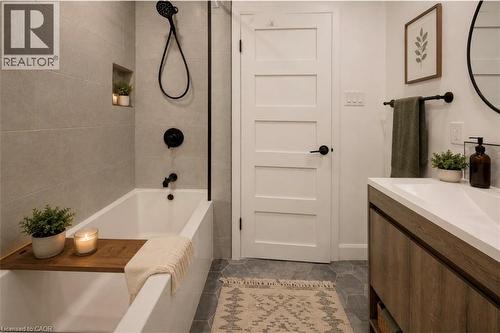 Bathroom featuring a soaking tub with dark-toned fixtures, a tiled accent wall, and a built-in shower niche - 244 Royal Street, Waterloo, ON - Indoor Photo Showing Bathroom