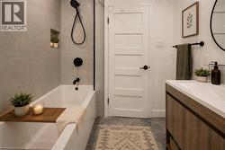 Bathroom featuring a soaking tub with dark-toned fixtures, a tiled accent wall, and a built-in shower niche - 