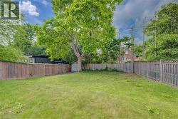 Expansive yard featuring a mature tree, wooden fencing, and a storage shed - 