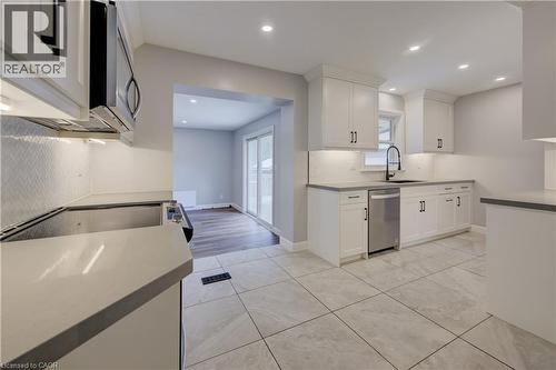 Contemporary kitchen featuring white cabinetry, light countertops, stainless steel appliances, and large format tile flooring - 244 Royal Street, Waterloo, ON - Indoor Photo Showing Kitchen