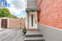 Entry with red brick and gray siding, white door with vertical glass insert, covered porch with steps, and a wood-slat fence - 