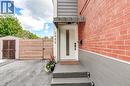 Entry with red brick and gray siding, white door with vertical glass insert, covered porch with steps, and a wood-slat fence - 2488 Brookhurst Road, Mississauga, ON  - Outdoor With Exterior 