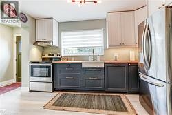 Modern kitchen featuring two-tone cabinetry, stainless steel appliances, wood-finish countertops, and an apron-front sink - 