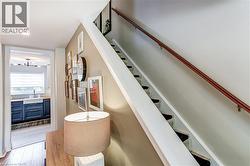 Hardwood flooring, wood stair railing, recessed lighting, white farmhouse sink, and dark blue cabinetry - 