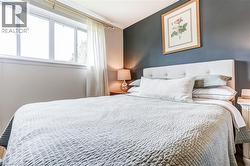 Large window with white trim, a tufted upholstered headboard, and a contrasting accent wall - 