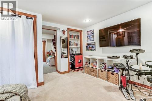 Recessed lighting, wood-finish trim, built-in shelving, mounted television, and carpeting - 2488 Brookhurst Road, Mississauga, ON - Indoor Photo Showing Other Room