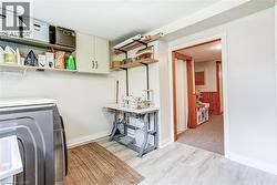 White cabinetry, wall-mounted shelving, wood-finish flooring, and a cased opening with wood trim - 