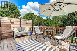 Expansive wood deck with a privacy fence featuring integrated sconce lighting, and a wood railing overlooking mature trees - 