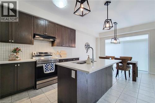 Kitchen featuring dark wood-finish cabinetry, white tile backsplash, stainless steel appliances, a center island with a sink, and pendant lighting - 11 Esther Crescent, Thorold, ON - Indoor Photo Showing Kitchen With Double Sink With Upgraded Kitchen