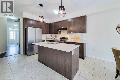 Kitchen featuring dark wood-finish cabinetry, a central island with a white countertop, and stainless steel appliances - 11 Esther Crescent, Thorold, ON - Indoor Photo Showing Kitchen With Stainless Steel Kitchen With Double Sink