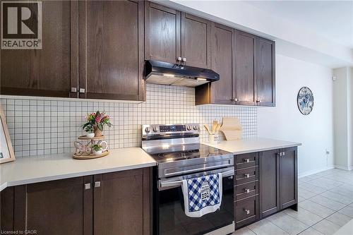 Dark wood-finish cabinetry with silver hardware, white square tile backsplash, and light countertops - 11 Esther Crescent, Thorold, ON - Indoor Photo Showing Kitchen