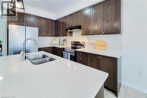 Kitchen featuring dark wood-finish cabinetry, white square tile backsplash, stainless steel appliances, and white countertops - 11 Esther Crescent, Thorold, ON - Indoor Photo Showing Kitchen With Double Sink With Upgraded Kitchen