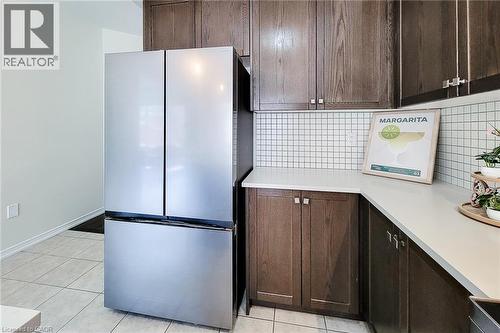 Stainless steel French door refrigerator, dark wood-finish cabinetry with silver-tone hardware, white square tile backsplash, and light-toned countertops - 11 Esther Crescent, Thorold, ON - Indoor Photo Showing Kitchen
