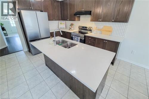 Kitchen featuring a large center island with an undermount double sink, stainless steel appliances, dark wood-finish cabinetry, and a white subway tile backsplash - 11 Esther Crescent, Thorold, ON - Indoor Photo Showing Kitchen With Stainless Steel Kitchen With Double Sink