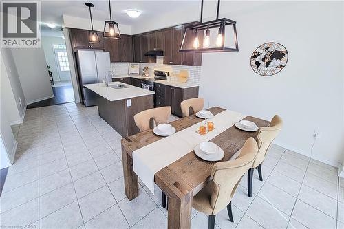 Kitchen featuring dark wood-finish cabinetry, stainless steel appliances, a center island with sink, and a white subway tile backsplash - 11 Esther Crescent, Thorold, ON - Indoor Photo Showing Dining Room