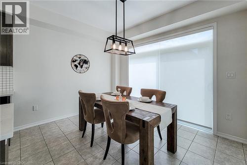 Dining area featuring a contemporary linear chandelier, large sliding glass doors with roller shades, and tile flooring - 11 Esther Crescent, Thorold, ON - Indoor Photo Showing Dining Room