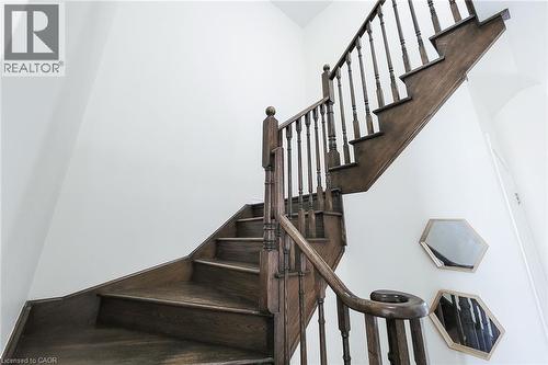Wood-finish staircase with turned balusters and a curved handrail, set against crisp white walls - 11 Esther Crescent, Thorold, ON - Indoor Photo Showing Other Room