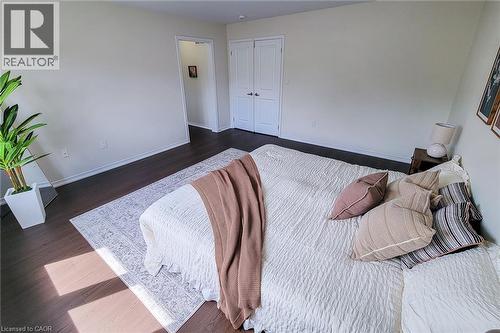 Dark wood-finish flooring with light wall tones - 11 Esther Crescent, Thorold, ON - Indoor Photo Showing Bedroom