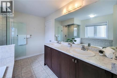 Dual basin vanity with stone-finish countertop, dark wood-finish cabinetry, and an expansive mirror - 11 Esther Crescent, Thorold, ON - Indoor Photo Showing Bathroom