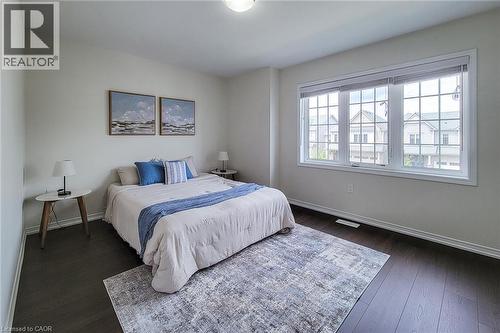 Dark wood-finish flooring, white walls, and a large multi-pane window create a bright and inviting atmosphere - 11 Esther Crescent, Thorold, ON - Indoor Photo Showing Bedroom
