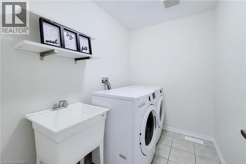 Utility room featuring tiled flooring, a built-in utility sink with a chrome faucet, and integrated shelving - 11 Esther Crescent, Thorold, ON - Indoor Photo Showing Laundry Room