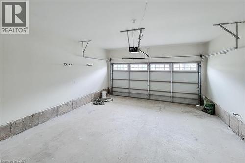 Attached garage featuring a paneled door with transom-style windows, an automatic opener, and concrete flooring - 11 Esther Crescent, Thorold, ON - Indoor Photo Showing Garage