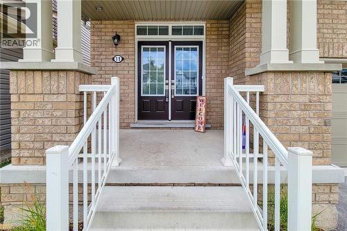 Brick facade with white column accents, concrete steps with white railings, and double entry doors with integrated glass panels - 11 Esther Crescent, Thorold, ON - Outdoor With Exterior