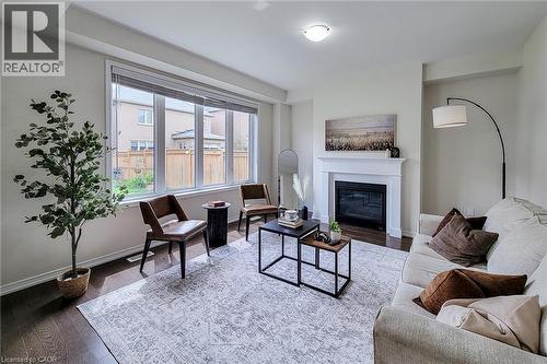 Living space featuring dark wood-finish flooring, a white mantel fireplace, and a large window with horizontal blinds - 11 Esther Crescent, Thorold, ON - Indoor Photo Showing Living Room With Fireplace