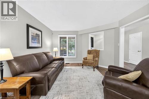 Bay window with plantation shutters, light gray wall finishes, wood-finish flooring, and white trim - 43 Liam Drive, Ancaster, ON - Indoor Photo Showing Living Room