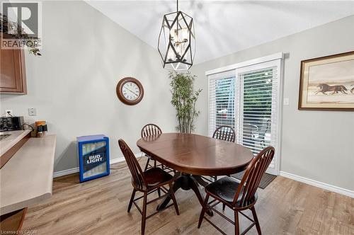 Vaulted ceiling, wood-finish flooring, sliding glass door, white horizontal blinds, and a geometric pendant light fixture - 43 Liam Drive, Ancaster, ON - Indoor Photo Showing Dining Room