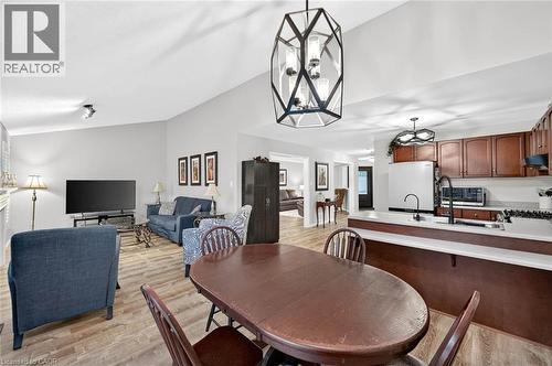 Vaulted ceilings, wood-finish flooring, kitchen with dark wood cabinetry and light countertops, modern geometric pendant lighting, and recessed living room lighting - 43 Liam Drive, Ancaster, ON - Indoor Photo Showing Dining Room