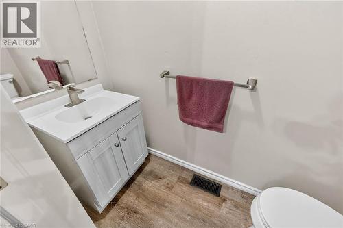 Vanity with integrated sink, wood-finish flooring, and white toilet - 43 Liam Drive, Ancaster, ON - Indoor Photo Showing Bathroom