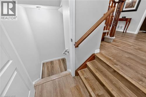 Wood-finish flooring throughout, wood staircase with coordinating handrail, and light gray wall paint - 43 Liam Drive, Ancaster, ON - Indoor Photo Showing Other Room