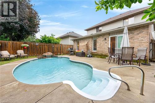 Backyard oasis featuring an in-ground pool with built-in steps, a rock waterfall feature, and concrete pool decking - 43 Liam Drive, Ancaster, ON - Outdoor With In Ground Pool With Deck Patio Veranda