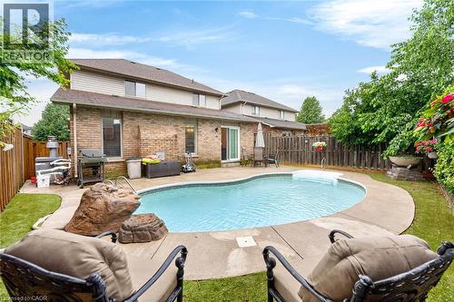 Pebble-finish pool with concrete surround, brick and siding exterior, and privacy fencing - 43 Liam Drive, Ancaster, ON - Outdoor With In Ground Pool With Deck Patio Veranda