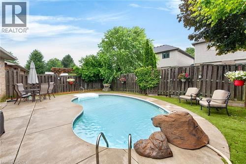 Curved inground pool with concrete surround, expansive lawn area, and privacy fencing - 43 Liam Drive, Ancaster, ON - Outdoor With In Ground Pool