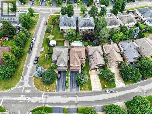 Aerial view showcasing a residential property featuring a swimming pool, manicured lawns with mature landscaping, two-car driveway, and a tree-lined neighborhood setting with multiple homes visible th - 43 Liam Drive, Ancaster, ON - Outdoor