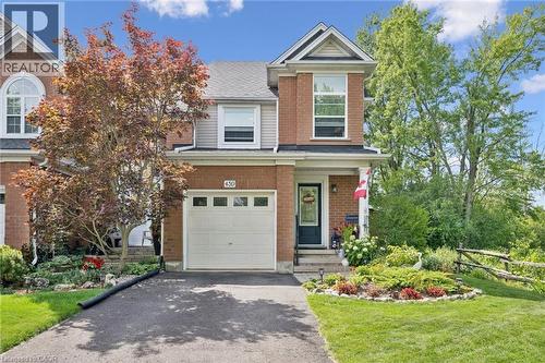 Brick exterior with vinyl siding accents, attached garage, paved driveway, mature trees, and landscaped front yard - 439 Beaver Creek Road, Waterloo, ON - Outdoor With Facade
