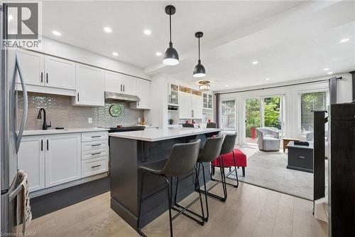 Kitchen featuring white cabinetry, a gray tiled backsplash, stainless steel appliances, and a central island with counter seating - 439 Beaver Creek Road, Waterloo, ON - Indoor Photo Showing Kitchen With Upgraded Kitchen