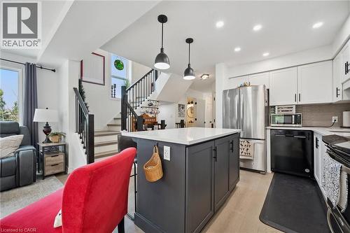 Open-concept kitchen featuring a center island with pendant lighting, white upper cabinetry, and stainless steel appliances - 439 Beaver Creek Road, Waterloo, ON - Indoor Photo Showing Kitchen With Upgraded Kitchen