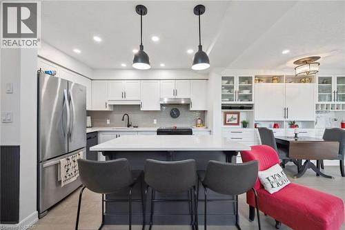Contemporary kitchen featuring a center island with seating, pendant lighting, stainless steel appliances, white cabinetry, and a tile backsplash - 439 Beaver Creek Road, Waterloo, ON - Indoor Photo Showing Kitchen With Upgraded Kitchen