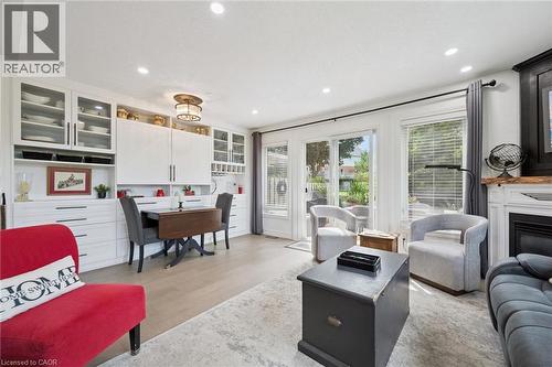 Built-in white cabinetry with glass-front storage, recessed lighting, wood-finish flooring, and a sliding glass door - 439 Beaver Creek Road, Waterloo, ON - Indoor Photo Showing Living Room