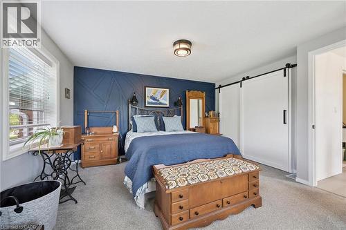 Wall-to-wall carpeting, a window with blinds, a modern ceiling light, and a blue accent wall with geometric detailing - 439 Beaver Creek Road, Waterloo, ON - Indoor Photo Showing Bedroom