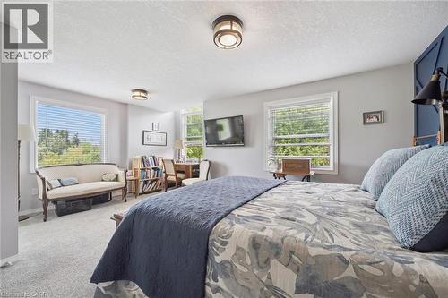 Recessed lighting fixtures, multiple windows with blinds, built-in shelving, carpeted flooring, and accent wall paneling - 439 Beaver Creek Road, Waterloo, ON - Indoor Photo Showing Bedroom
