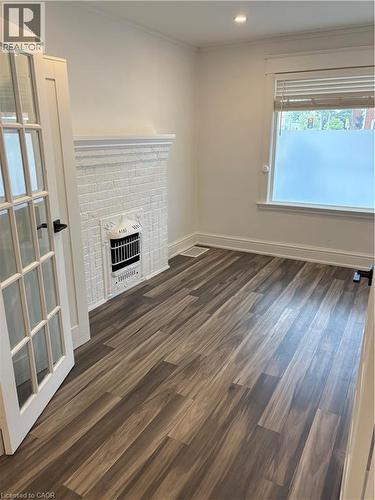 Unfurnished living room featuring wood finished floors, a fireplace, ornamental molding, and heating unit - 1090 Cannon Street E Unit# 2, Hamilton, ON - Indoor Photo Showing Other Room With Fireplace