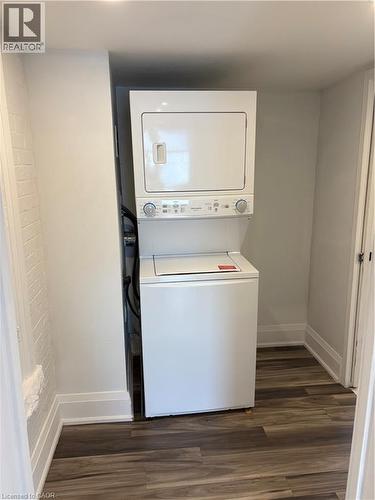 Laundry room with stacked washer and clothes dryer and dark wood-style floors - 1090 Cannon Street E Unit# 2, Hamilton, ON - Indoor Photo Showing Laundry Room