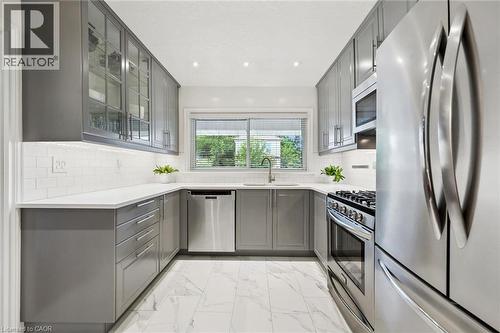U-shaped kitchen featuring grey cabinetry, stainless steel appliances, white subway tile backsplash, and white countertops - 49 East Street, Cambridge, ON - Indoor Photo Showing Kitchen With Stainless Steel Kitchen With Upgraded Kitchen