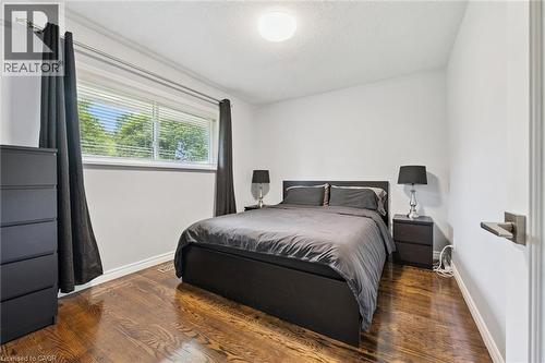 Hardwood flooring, painted white walls, single window with blinds, overhead lighting, and a metal door handle - 49 East Street, Cambridge, ON - Indoor Photo Showing Bedroom