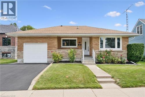 Brick exterior with stone accents, attached garage, concrete walkway, established landscaping, and a pitched roof - 49 East Street, Cambridge, ON - Outdoor With Facade